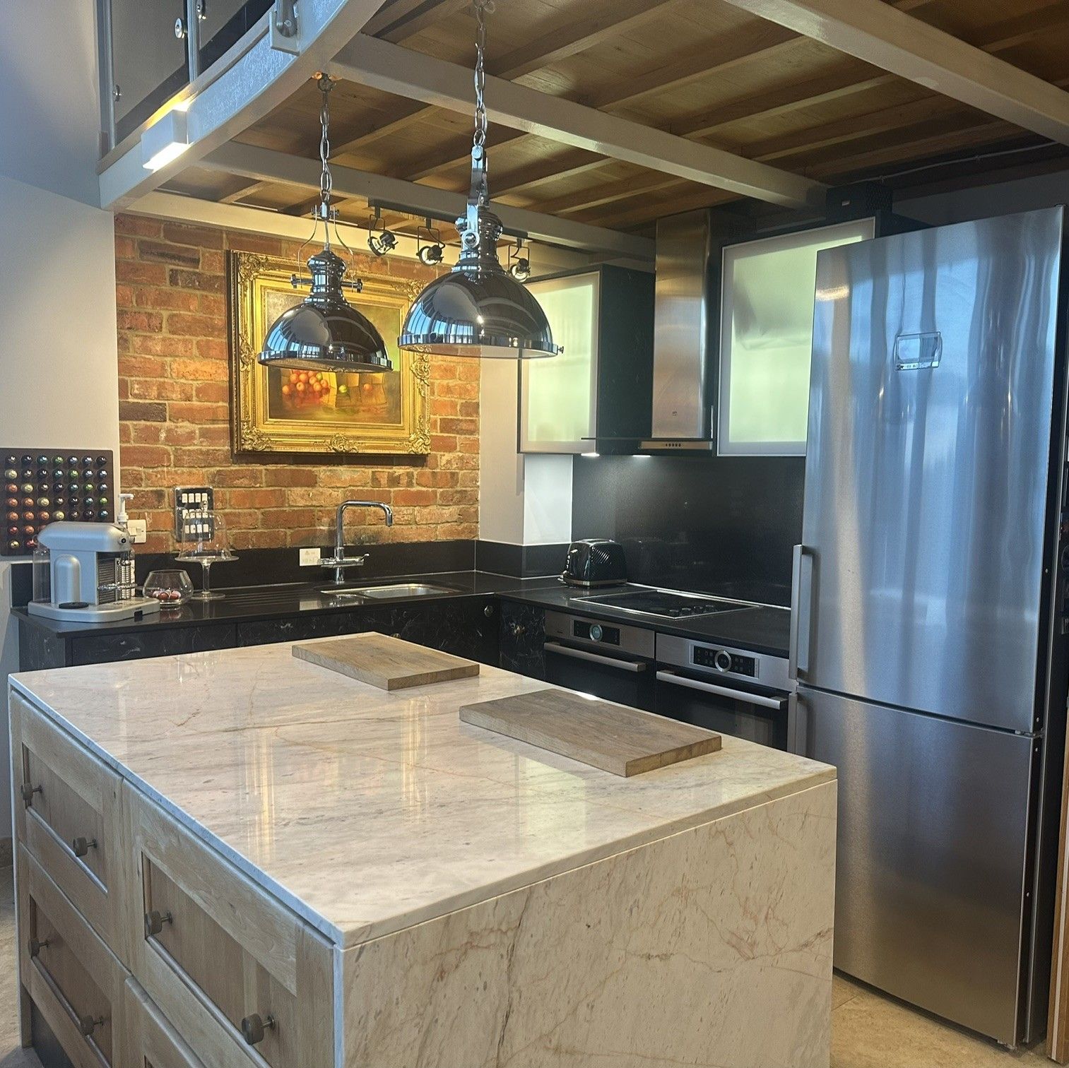 Kitchen island in marble with industrial pendants and exposed brick