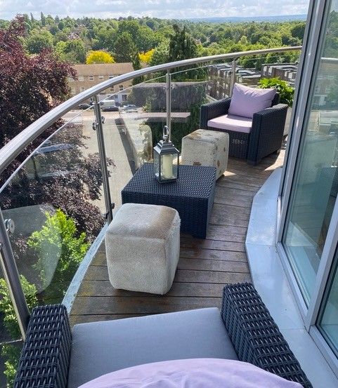 Curved private balcony with rattan seating and treetop views